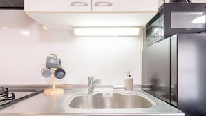 Quarto quádruplo luxo, sacada | Cozinha privada | Geladeira, micro-ondas, cooktop, talheres/pratos/utensílios de cozinha