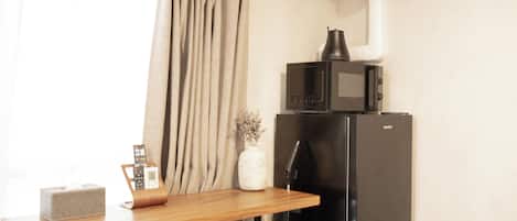 A kitchenette with a microwave, refrigerator, and a wooden table with chairs.