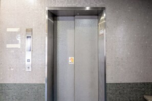 An elevator with a metallic interior and a tiled wall with a green border. - b&Dotonbori 1 (Chuo Ward)