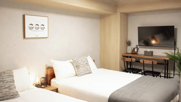Quarto de hotel com cama, mesas de cabeceira, escrivaninha com cadeiras, televisão e um quadro na parede.