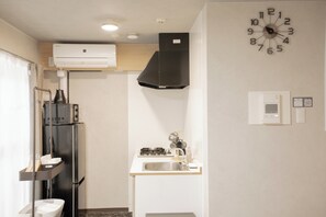 A compact kitchen with a gas stove, sink, and a clock on the wall. - b&Dotonbori 1 (Chuo Ward)