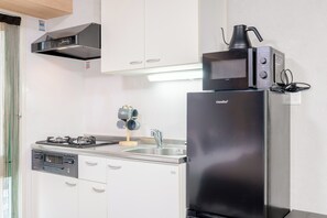 A compact kitchen with a black refrigerator, a stove, and a coffee maker. - b&Dotonbori 1 (Chuo Ward)
