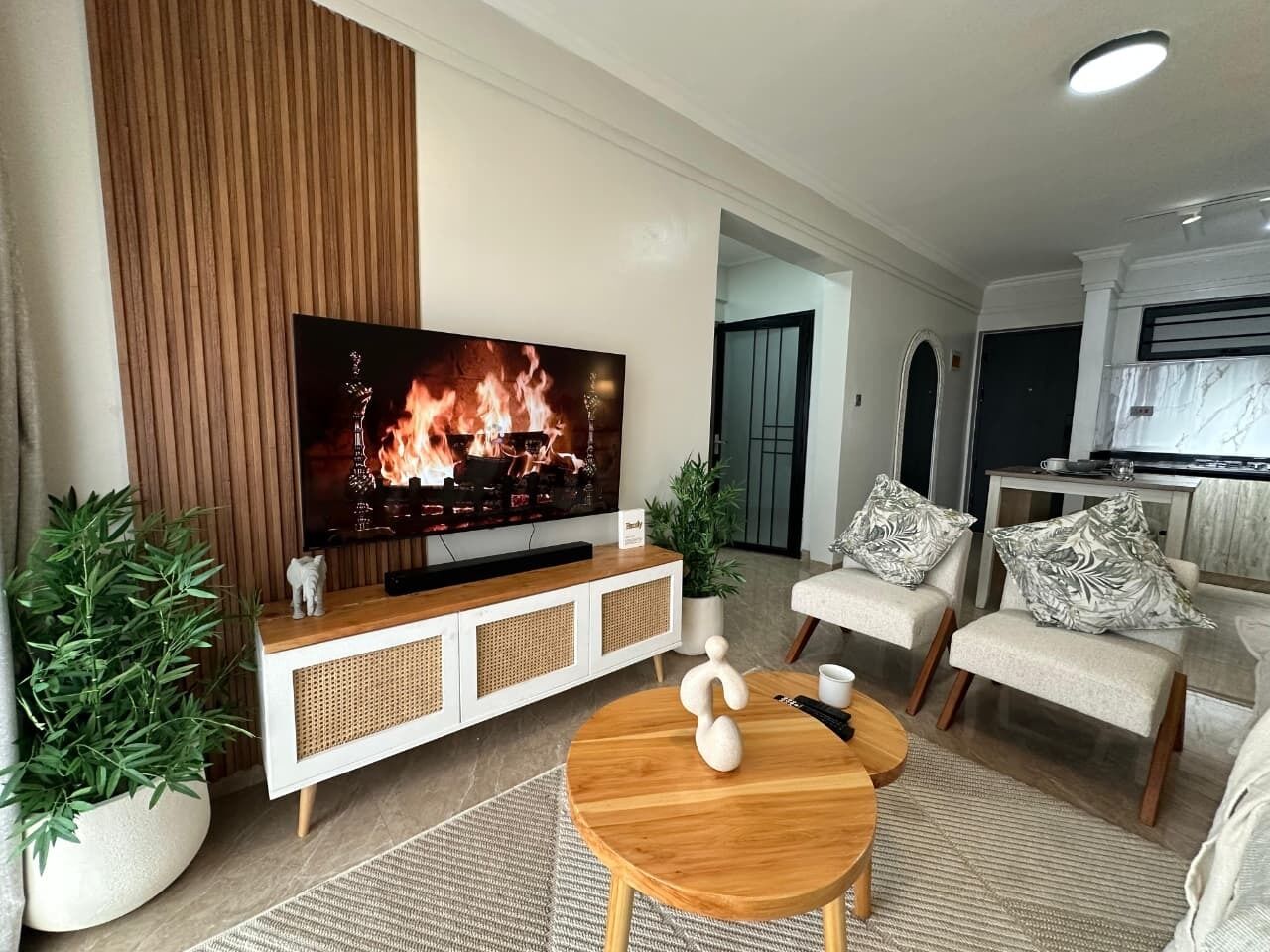 A modern living room with a flat-screen TV, a wooden coffee table, and a sofa with patterned cushions.