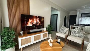 A modern living room with a flat-screen TV, a wooden coffee table, and a sofa with patterned cushions.