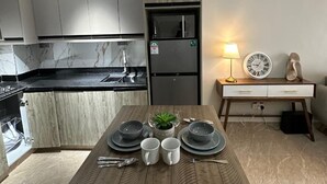 A modern kitchen with a built-in island, a refrigerator, and a dining area with a table set for two. - Padmore Residences Kilimani (Nairobi)