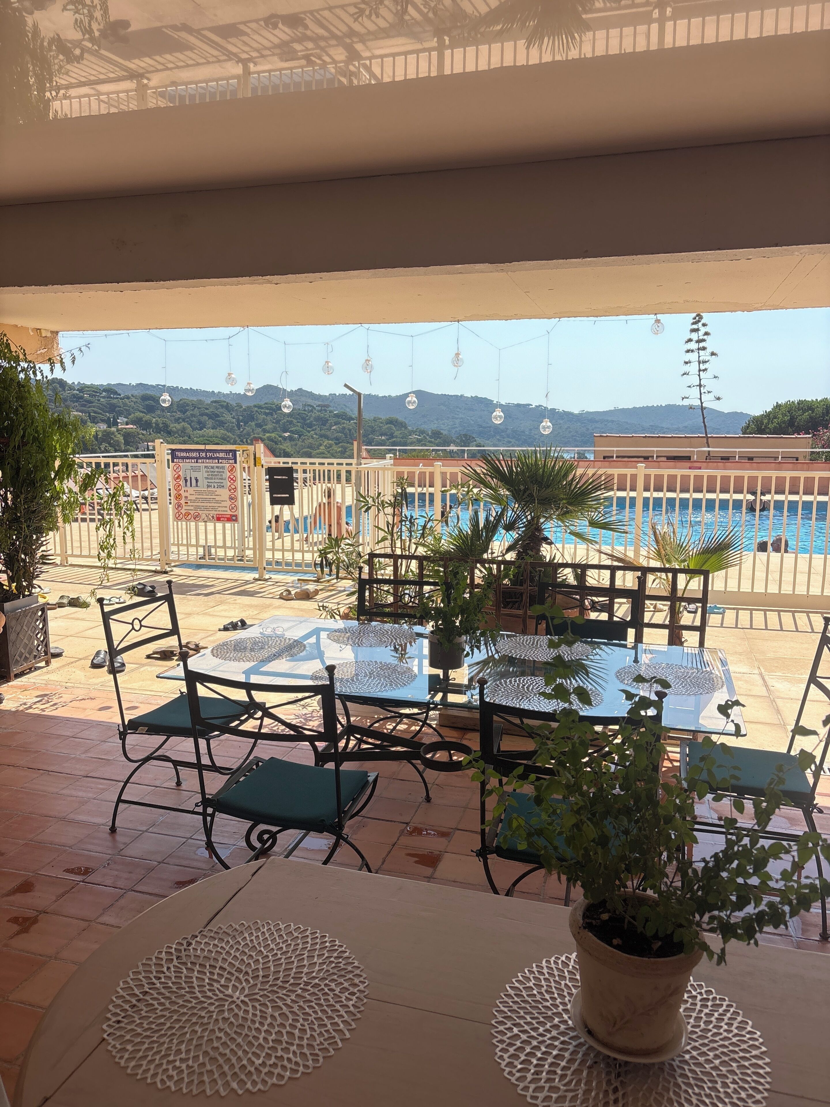 An outdoor patio area with a pool, tables, chairs, and potted plants.