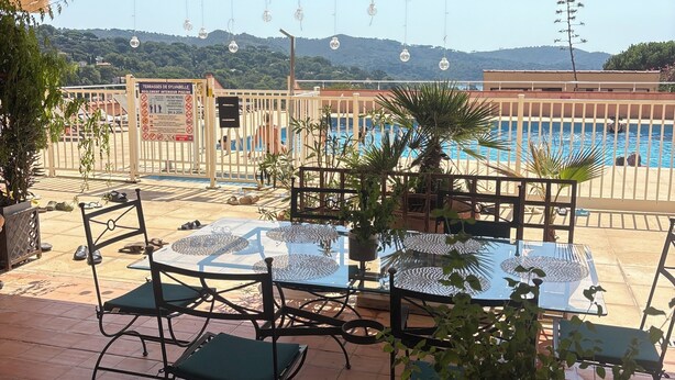 An outdoor patio area with a pool, tables, chairs, and potted plants. - Vacation Apartment (La Croix-Valmer)