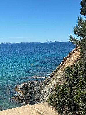 Eine Küstenlandschaft mit freiem Blick auf das Meer, felsigem Gelände und weit entfernten Landformen.