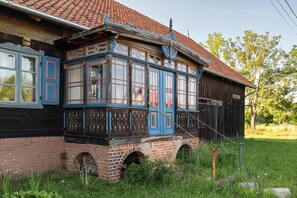 A traditional wooden building with a brick base, large windows with blue trim, and a tiled roof.