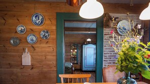 A wooden interior with a dining table, chairs, and various decorative plates on the wall. - Dom Dobrego Lata – Historic House in Drewnica (Drewnica)