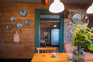 Ein Holzinterieur mit einem Esstisch, Stühlen und verschiedenen dekorativen Tellern an der Wand.