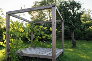 A wooden pergola structure with a platform, surrounded by greenery and trees. - Dom Dobrego Lata – Historic House in Żuławy (Drewnica)