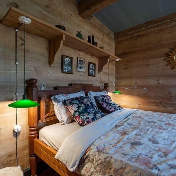 A wooden bedroom with a bed, pillows, and a hanging light fixture.