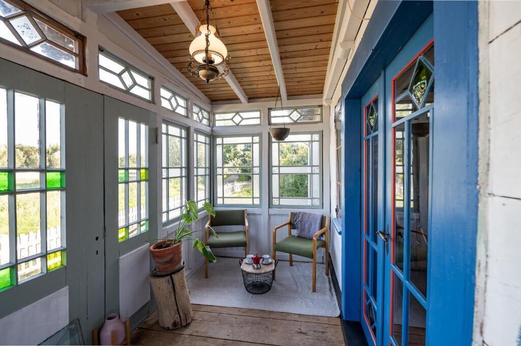 A room with large windows, a wooden ceiling, and a blue door.
