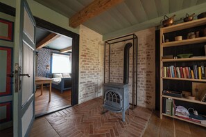 Ein Zimmer mit Backsteinwand, Holzboden, einem blauen Sofa, einem Bücherregal und einem alten Herd.