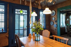Ein Holzespeisesaal mit Stühlen, einer Vase mit Blumen und hängenden Küchenutensilien.