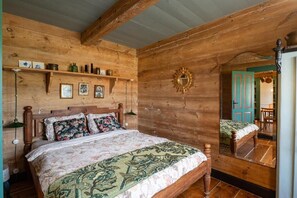 A wooden room with a bed, a mirror, and a shelf with decorative items. - Dom Dobrego Lata – Historic House in Żuławy (Drewnica)