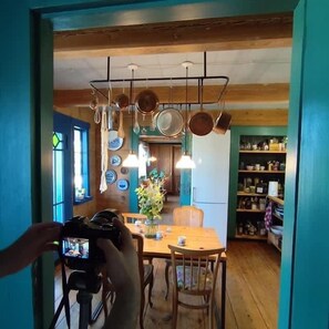 A kitchen with hanging pots, a dining table with chairs, and a camera capturing the scene.