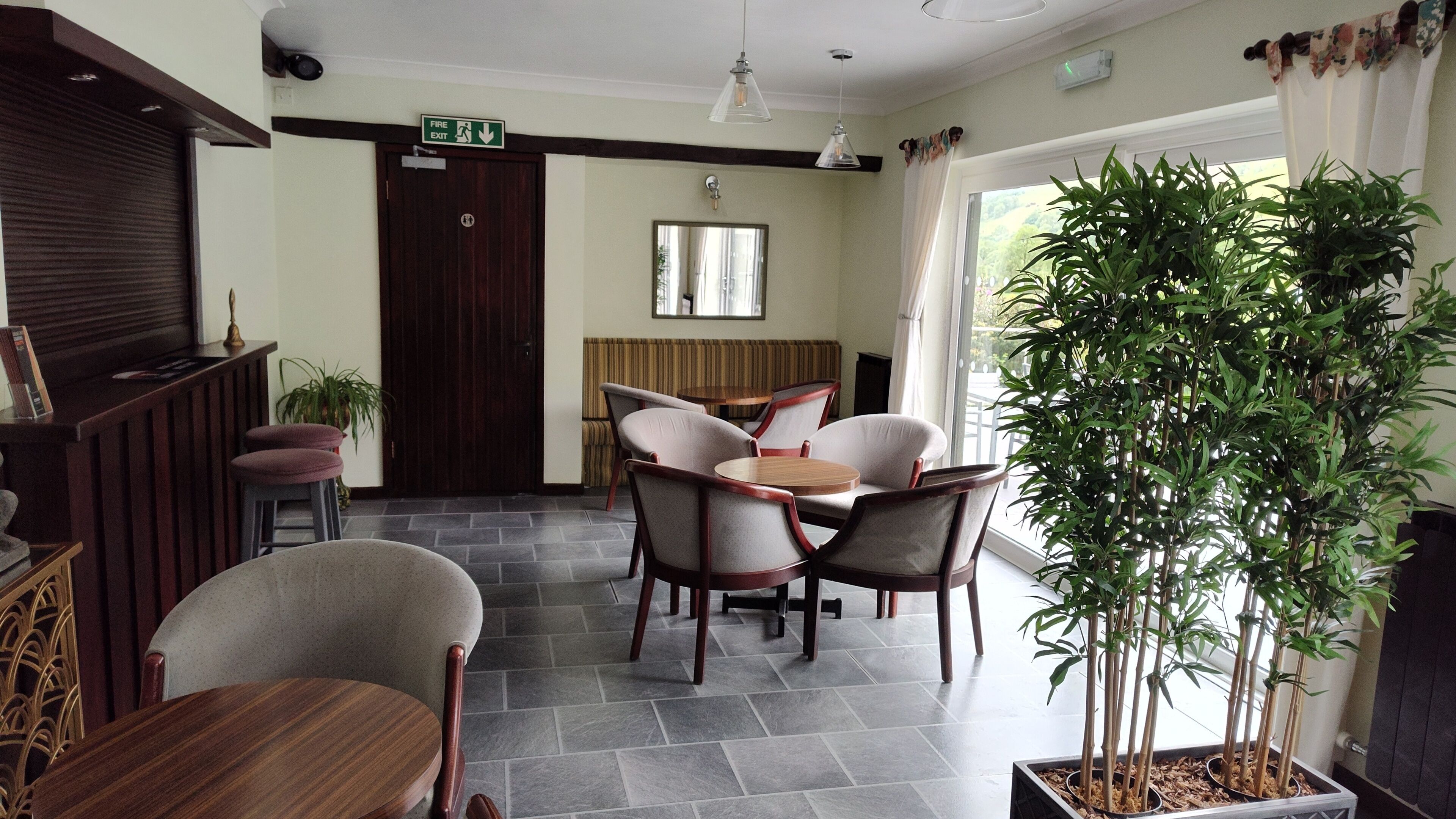 A hotel lobby with a reception desk, seating area, and a large potted plant.