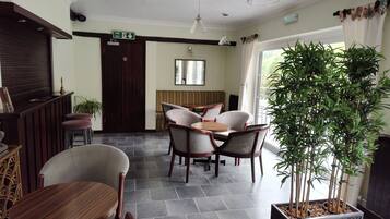 A hotel lobby with a reception desk, seating area, and a large potted plant.