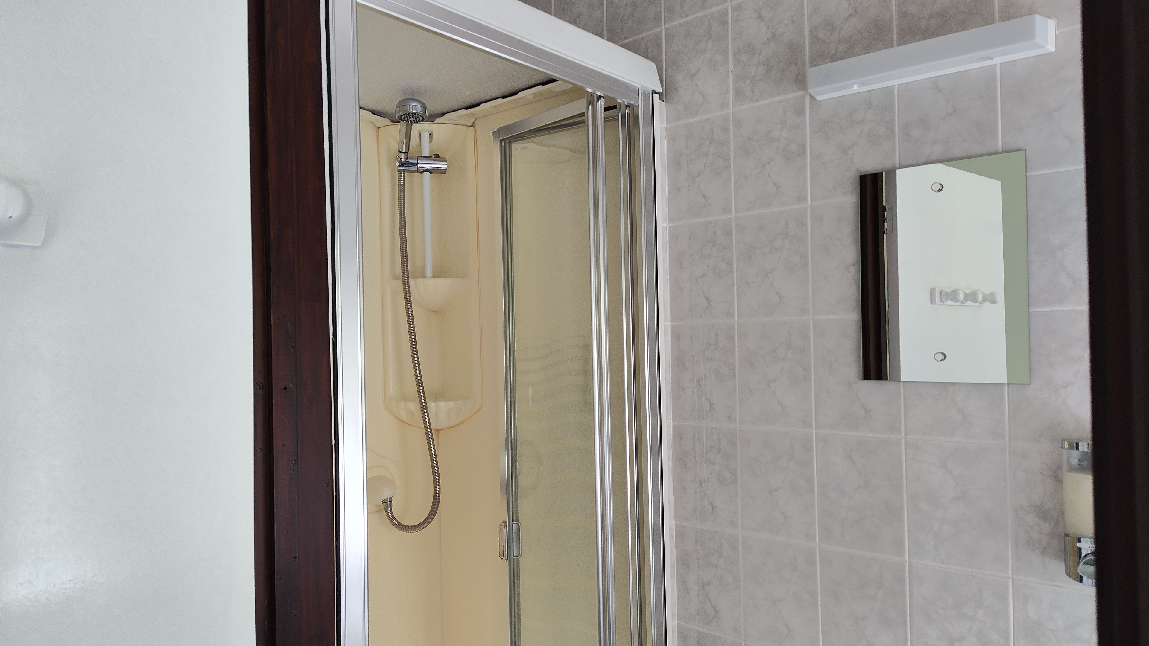 A shower with a glass door, a towel rack, and a mirror on the wall.