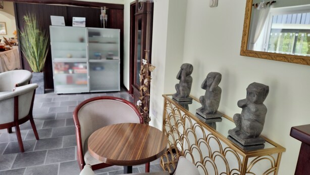 A dining area with a round wooden table and chairs, a glass cabinet with decorative items, and a wall-mounted mirror. - Dolbrodmaeth Riverside  (Machynlleth)