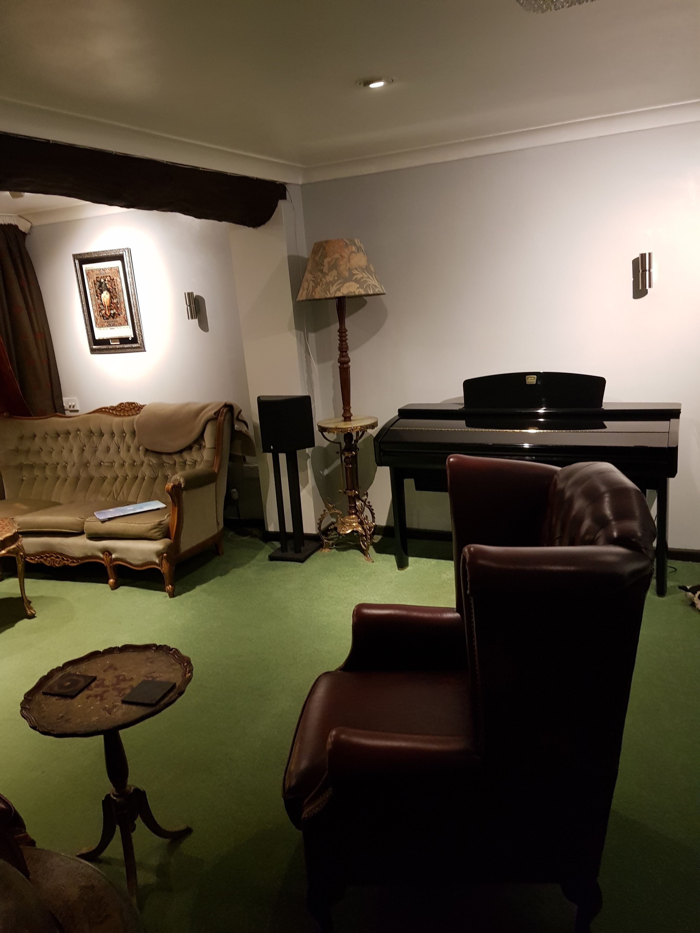 Una sala de estar con un sofá, una silla, una mesa, una lámpara y un piano.