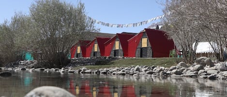 Une rangée de bâtiments aux toits rouges, avec une étendue d'eau paisible au premier plan.