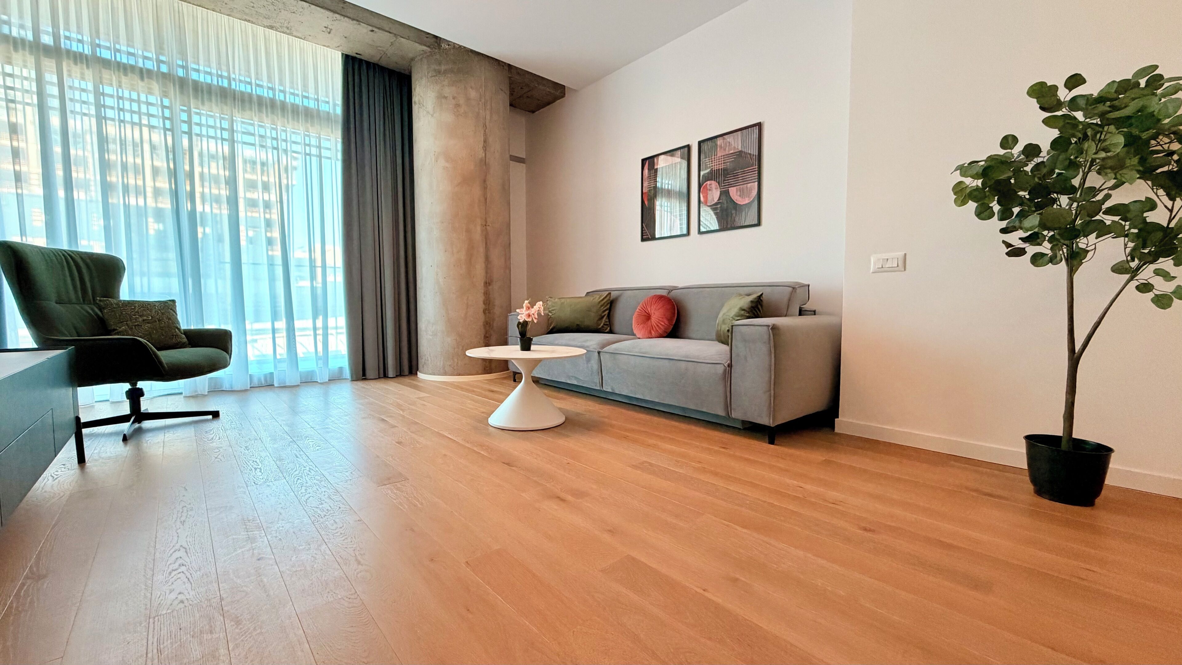 Uma sala de estar moderna com sofá, poltrona, mesinha de centro e planta em vaso.