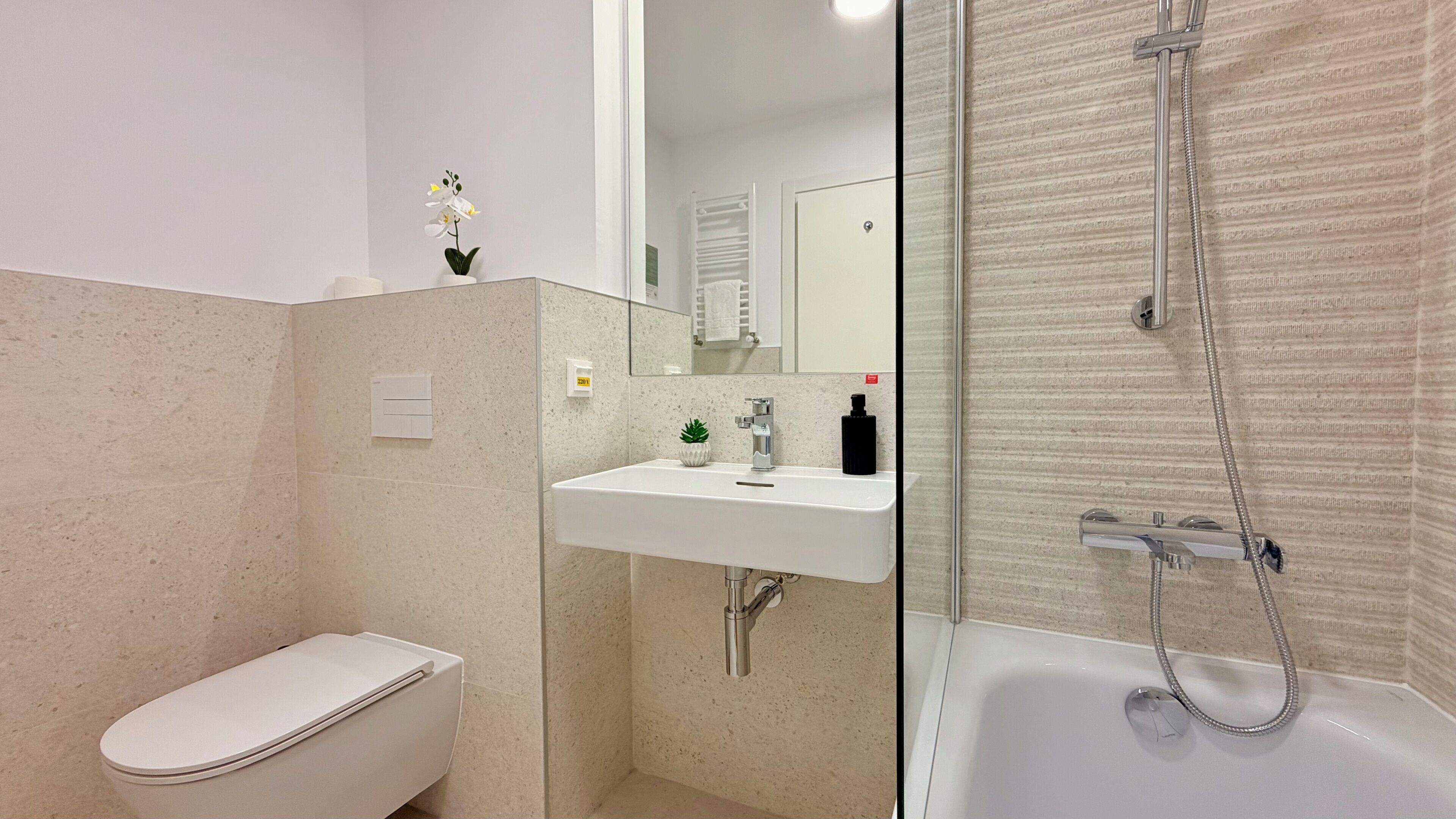 Een moderne badkamer met toilet, wastafel en douche.
