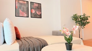 Un dormitorio con dos camas, una orquídea en maceta y una obra de arte abstracto en la pared.