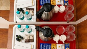 Two trays with coffee-making supplies, including kettles, cups, and coffee pods.