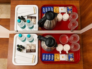 Two trays with coffee-making supplies, including kettles, cups, and coffee pods.