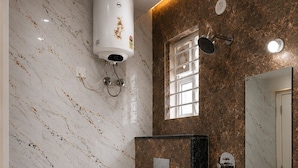 A bathroom with a toilet, bidet, and sink, marble walls, and a water heater.