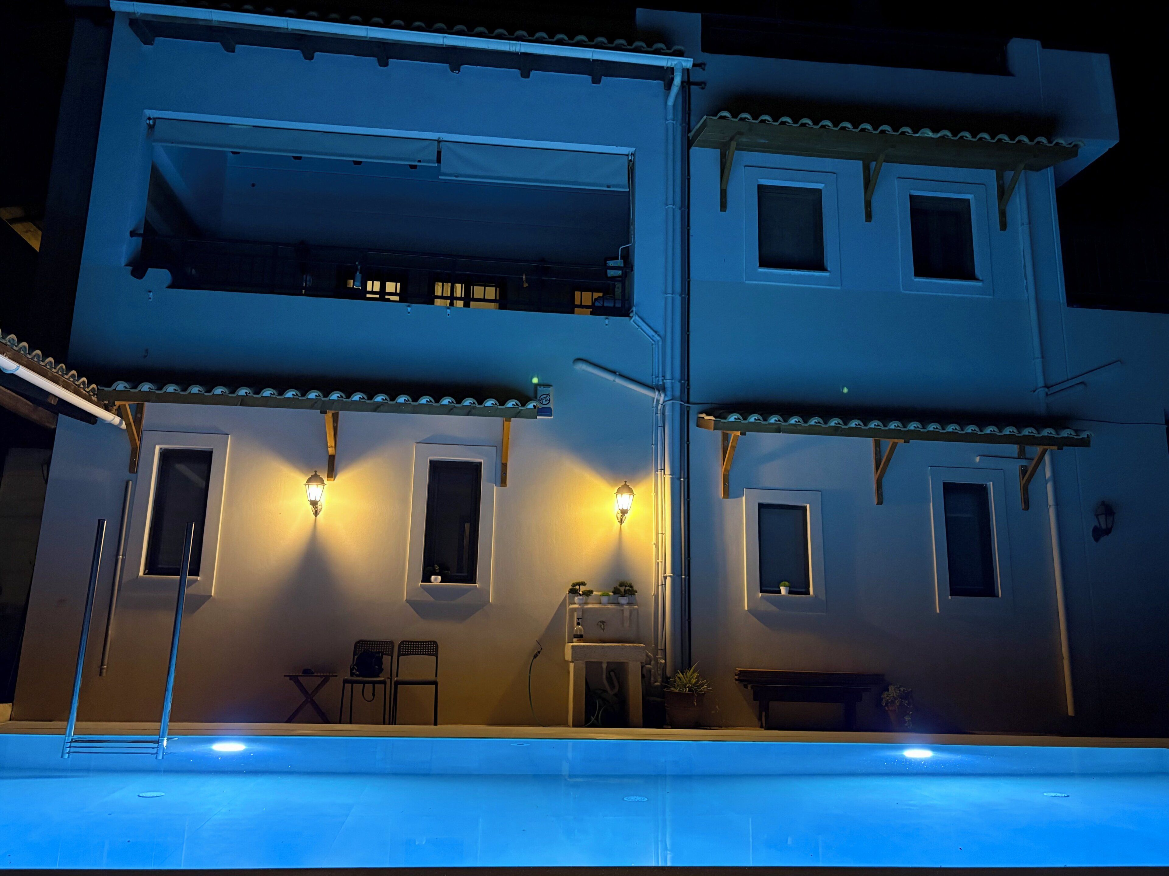 A two-story building with a balcony, a pool, and outdoor seating.