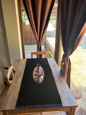A dining table with a black tablecloth, a wooden chair, and a tray with food items. - Papyrise Nest (Heraklion)