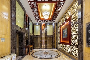Un vestíbulo de hotel con suelo de mármol, paneles decorativos y una araña.