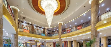 A multi-level atrium with a central fountain, marble columns, and a grand chandelier.