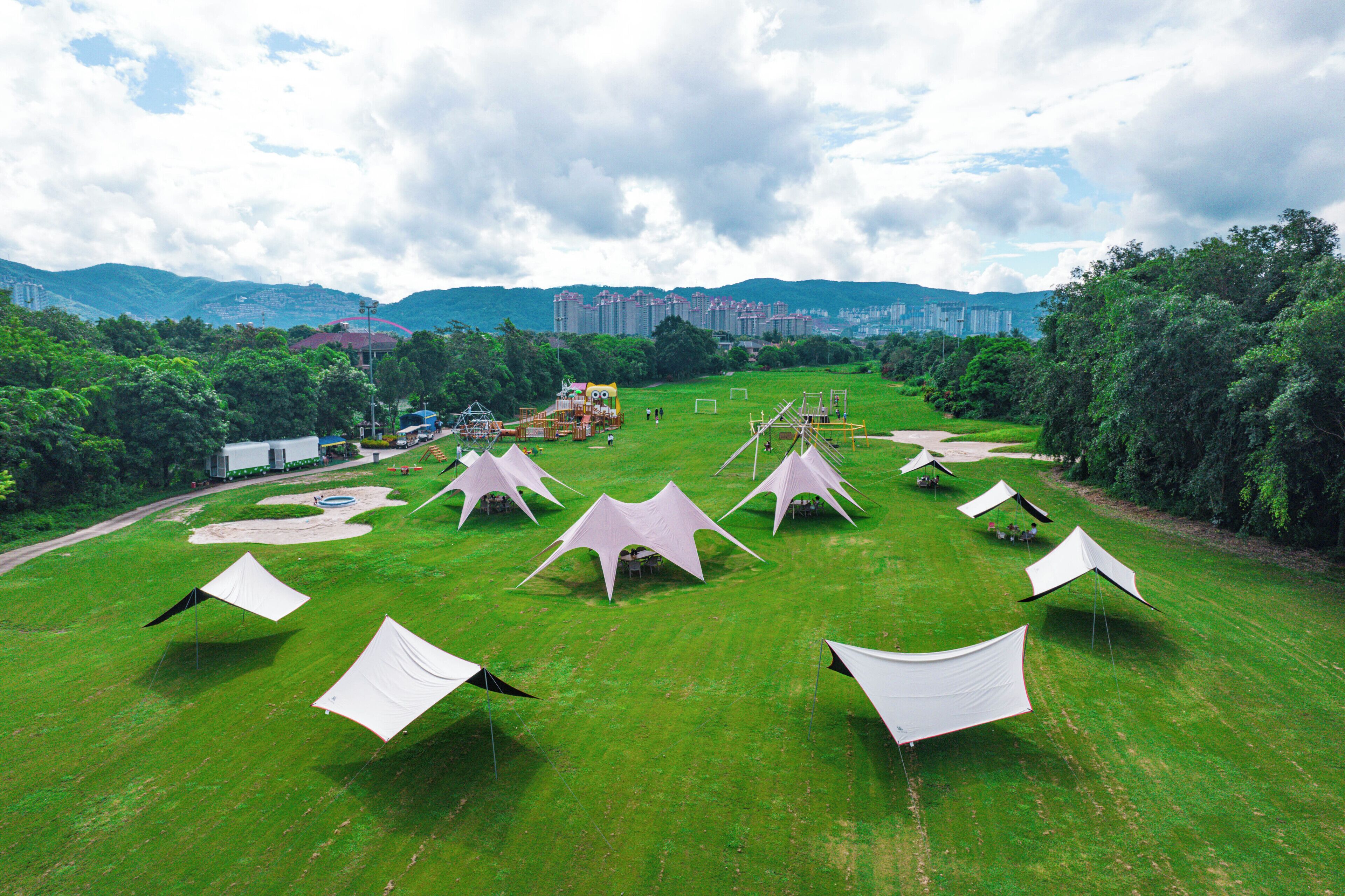 A grassy field with several white tents arranged in a semi-circle.