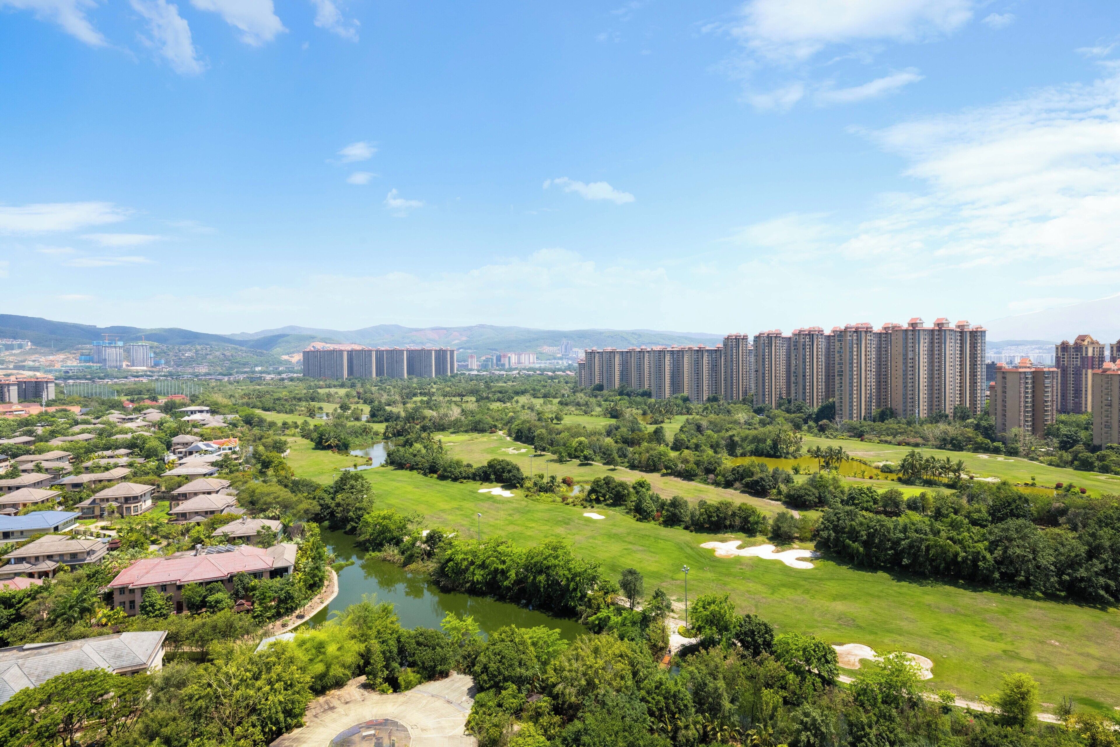 Zona residencial con edificios altos, un campo de golf y un río.