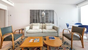 A modern living room with a sofa, two armchairs, a coffee table, and a dining area with chairs. - Les Terrasses B / Private Rooftop Pool in Tavira (tavira)