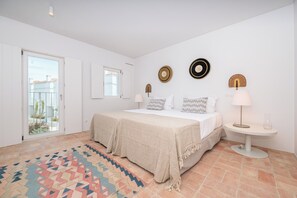 Une chambre à coucher avec un lit, une table de chevet avec une lampe, un tapis à motifs et une vue sur l’extérieur.