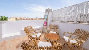 A rooftop terrace with wicker furniture, a small round table, and a view of the cityscape. - Les Terrasses B / Private Rooftop Pool in Tavira (tavira)