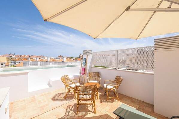 Une terrasse sur le toit avec une piscine, du mobilier d’extérieur et une vue sur le paysage urbain.