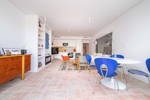 A modern living space with a kitchen, dining area, and a seating area with blue chairs. - Les Terrasses B / Private Rooftop Pool in Tavira (tavira)