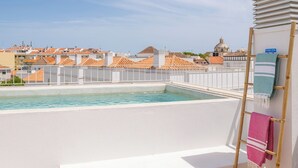 A rooftop swimming pool with a view of buildings and a wooden ladder with towels. - Les Terrasses B / Private Rooftop Pool in Tavira (tavira)