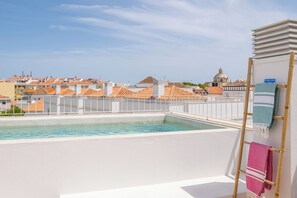 Ein Pool auf dem Dach mit Blick auf Gebäude und eine Holzleiter mit Handtüchern.