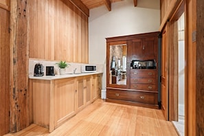 A kitchen with wooden cabinets, a countertop, a microwave, a coffee maker, and a potted plant. - Olinda Birch by Ready Set Stay (Olinda)