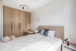 A bedroom with a bed, bedside table, and a wardrobe. - Kierbedzia Harmony Premium, Free Parking & WiFi (Warszawa)