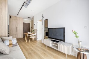 A modern living room with a flat-screen TV, wooden flooring, a dining area, and a sofa. - Kierbedzia Harmony Premium, Free Parking & WiFi (Warszawa)